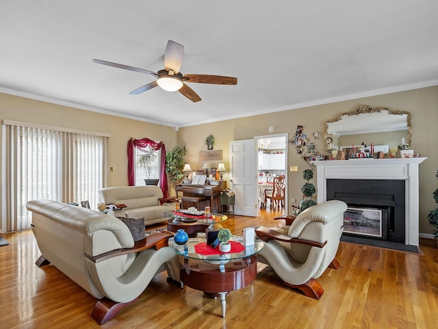 living room featuring ceiling fan, ornamental molding, and light hardwood / wood-style floors