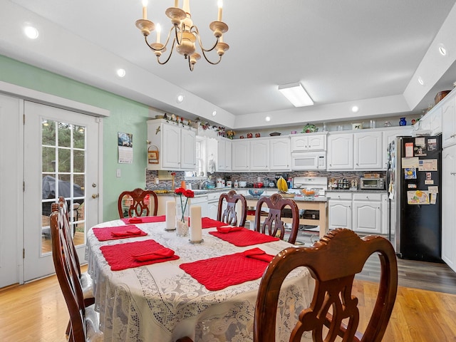 dining space with light hardwood / wood-style floors and a notable chandelier