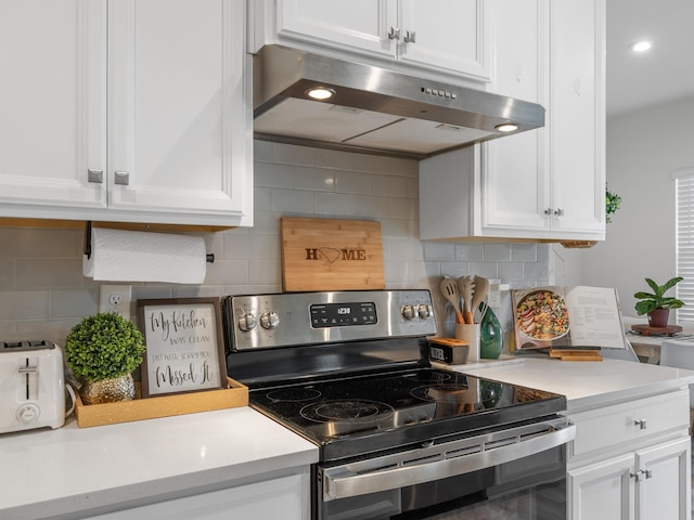 kitchen with backsplash, white cabinets, and electric range