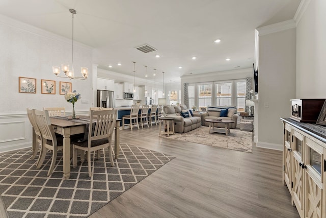 dining space featuring dark wood-type flooring, ornamental molding, and an inviting chandelier