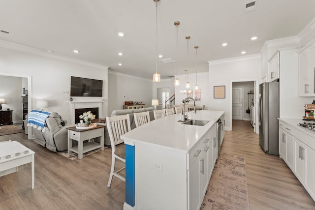 kitchen featuring appliances with stainless steel finishes, sink, white cabinetry, a kitchen island with sink, and a breakfast bar area