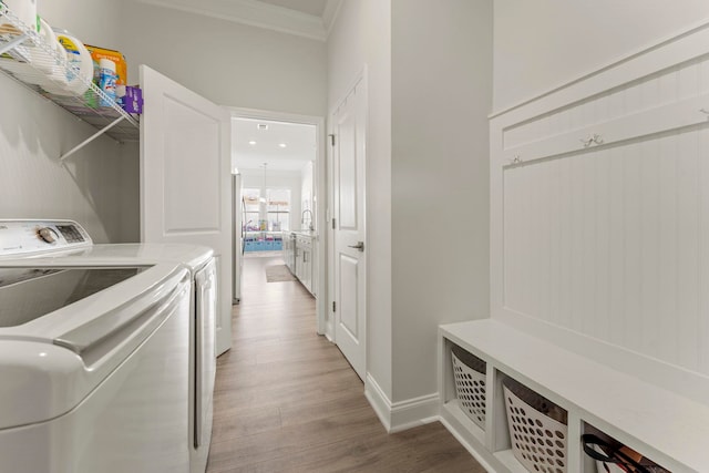 laundry room featuring hardwood / wood-style flooring, separate washer and dryer, and ornamental molding