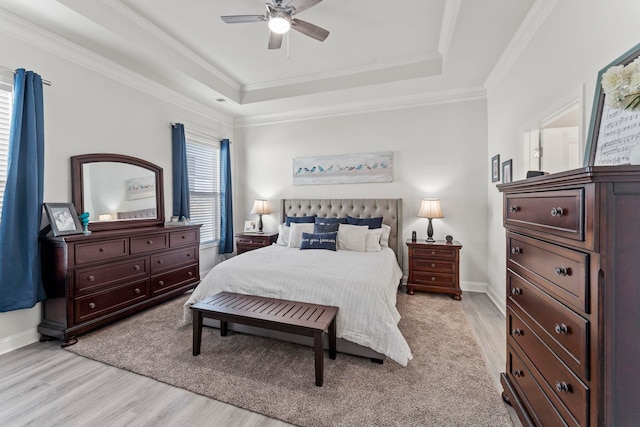 bedroom featuring ceiling fan, a raised ceiling, crown molding, and light hardwood / wood-style floors