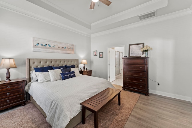 bedroom with crown molding, connected bathroom, ceiling fan, and a raised ceiling