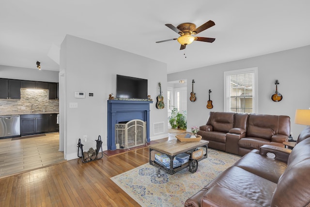 living room featuring ceiling fan, sink, and light hardwood / wood-style flooring