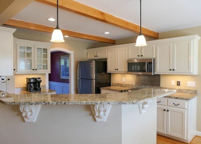 kitchen with white cabinets, stainless steel appliances, a kitchen breakfast bar, hanging light fixtures, and kitchen peninsula