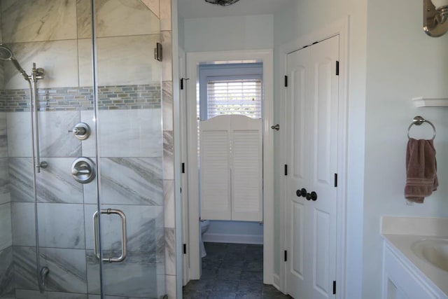 bathroom with a shower with shower door, toilet, and vanity