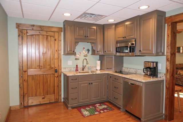 kitchen featuring light stone countertops, light hardwood / wood-style floors, gray cabinetry, sink, and stainless steel appliances