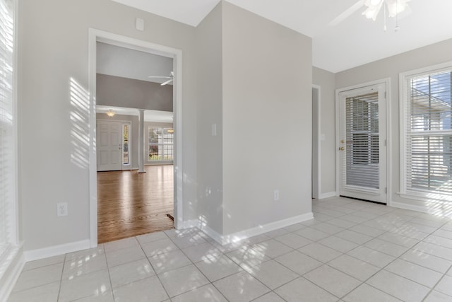 spare room featuring decorative columns, light tile patterned floors, and ceiling fan