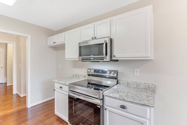 kitchen featuring white cabinets, hardwood / wood-style flooring, light stone countertops, and appliances with stainless steel finishes