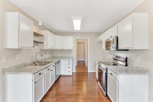 kitchen with sink, white cabinetry, light stone counters, hardwood / wood-style floors, and stainless steel appliances