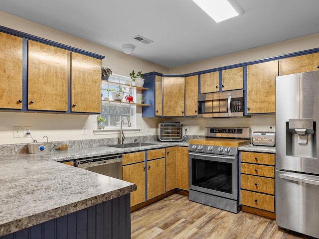 kitchen with appliances with stainless steel finishes, sink, and light wood-type flooring