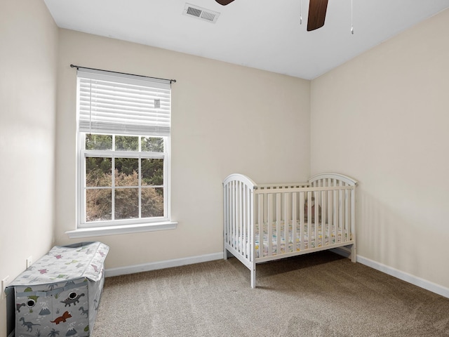 unfurnished bedroom featuring ceiling fan, carpet, and a crib