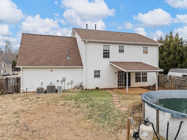 rear view of property featuring central AC unit, a lawn, a patio, and a covered pool