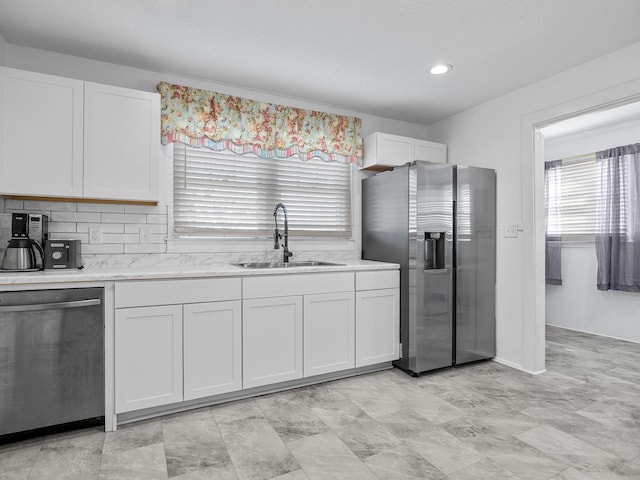 kitchen with sink, white cabinets, stainless steel appliances, and tasteful backsplash