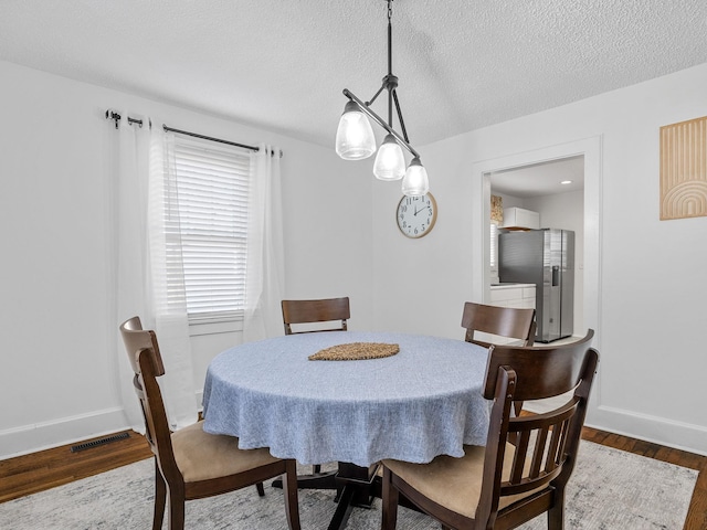 dining room featuring dark wood-type flooring and a textured ceiling