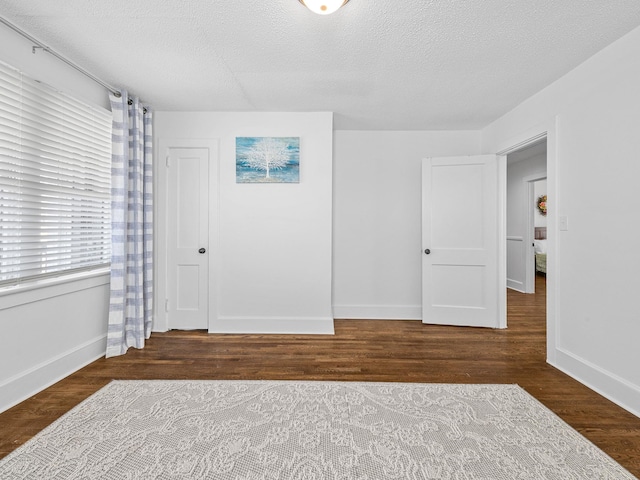 empty room with dark wood-type flooring and a textured ceiling