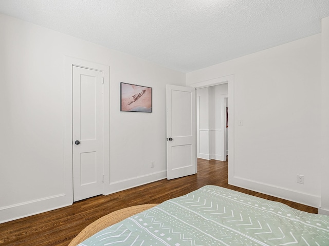 bedroom with dark hardwood / wood-style floors and a textured ceiling