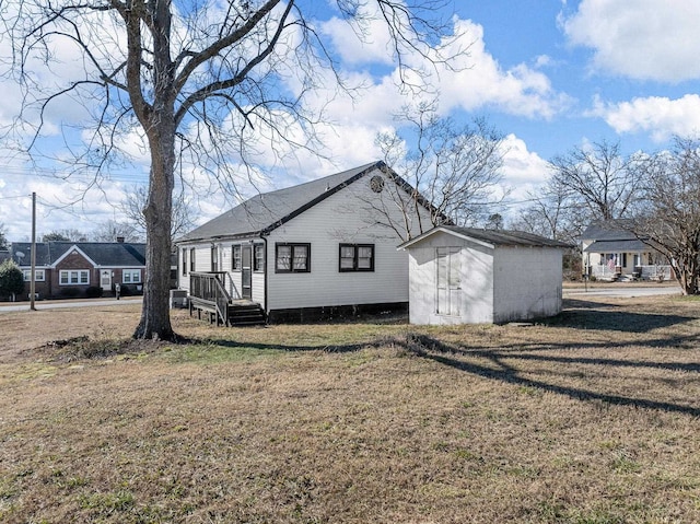 view of side of home featuring a lawn and a storage unit