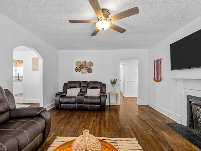 living room with sink, a textured ceiling, dark hardwood / wood-style floors, and a fireplace