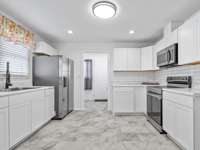 kitchen featuring sink, white cabinetry, a textured ceiling, and appliances with stainless steel finishes