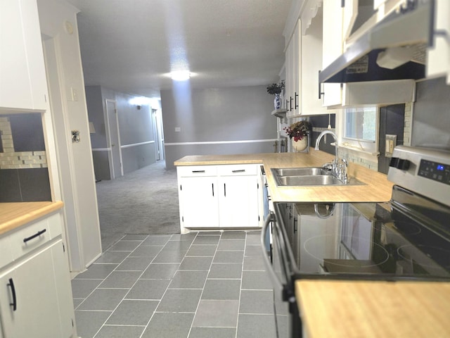 kitchen with white cabinetry, sink, stainless steel range with electric stovetop, dark colored carpet, and wood counters