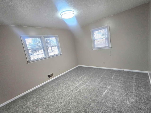 carpeted empty room with a textured ceiling