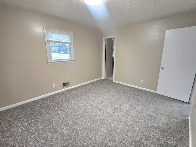 carpeted empty room featuring a textured ceiling