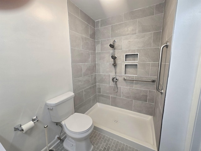 bathroom featuring tiled shower, toilet, and tile patterned floors