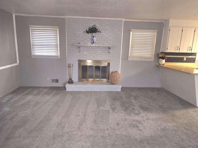 unfurnished living room featuring a brick fireplace, a textured ceiling, ornamental molding, and carpet floors