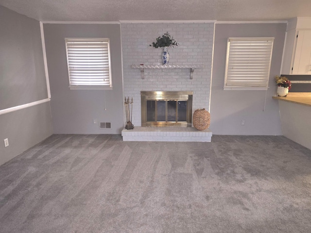 unfurnished living room with a fireplace, carpet flooring, a textured ceiling, and ornamental molding