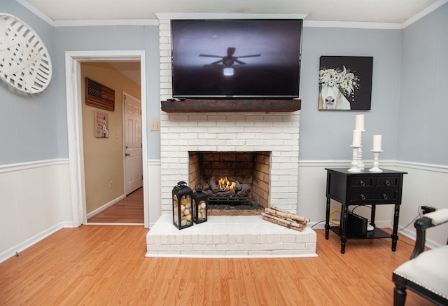 living room featuring a fireplace, hardwood / wood-style flooring, ceiling fan, and ornamental molding