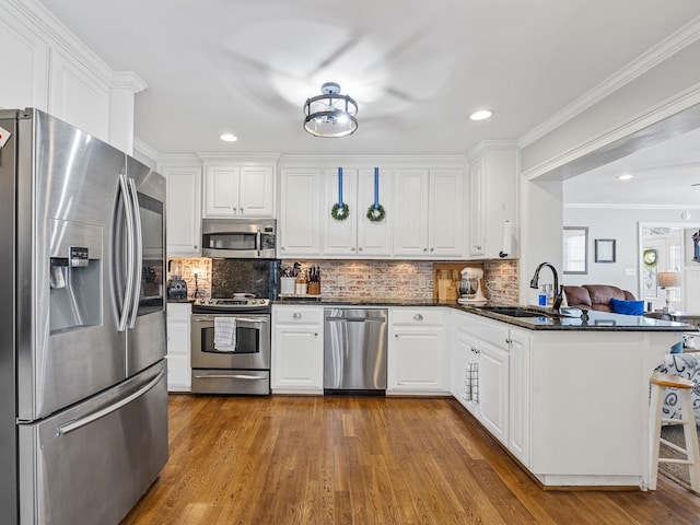 kitchen featuring sink, white cabinetry, kitchen peninsula, hardwood / wood-style flooring, and stainless steel appliances