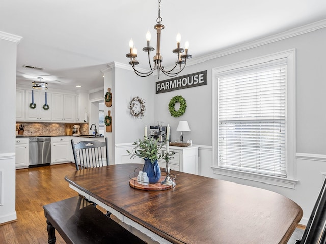 dining area with a notable chandelier, sink, crown molding, and hardwood / wood-style floors