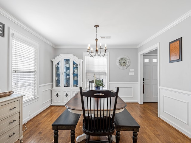 dining area with ornamental molding, a healthy amount of sunlight, a notable chandelier, and light hardwood / wood-style floors