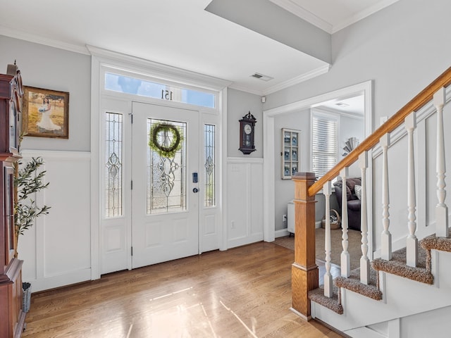 foyer with crown molding, a wealth of natural light, and light hardwood / wood-style floors