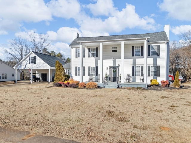 view of front of house featuring a carport, covered porch, and a front lawn