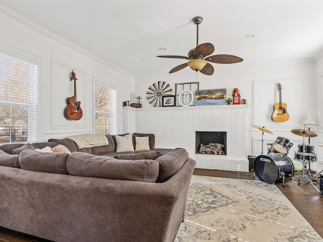 living room with ceiling fan, a brick fireplace, ornamental molding, and dark hardwood / wood-style flooring