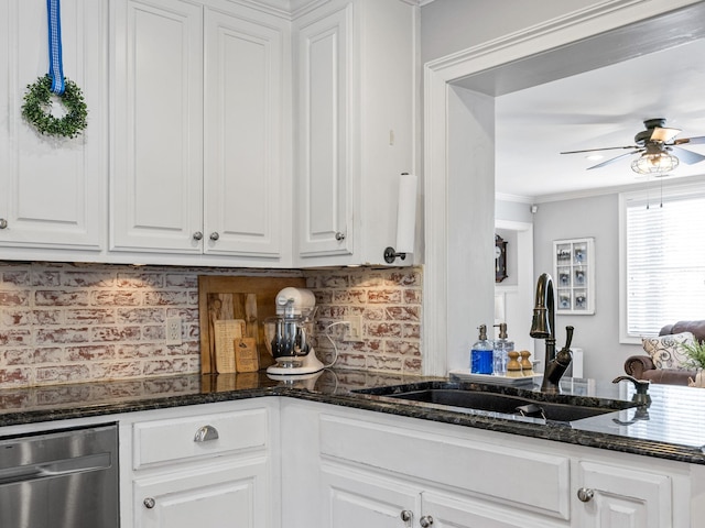 kitchen with sink, white cabinets, dark stone counters, ornamental molding, and ceiling fan