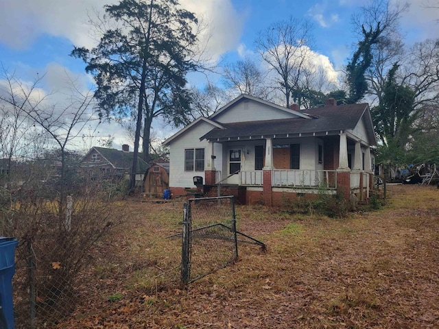 bungalow-style house featuring a porch and a storage unit