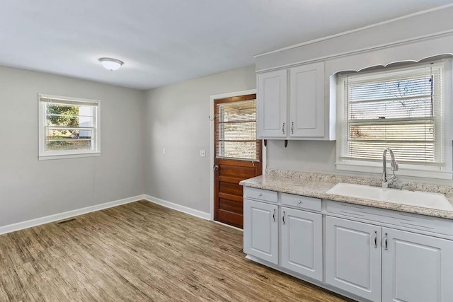 kitchen featuring white cabinetry, a healthy amount of sunlight, light hardwood / wood-style floors, and sink