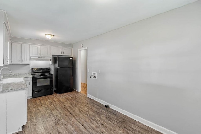 kitchen featuring sink, black appliances, light wood-type flooring, light stone countertops, and white cabinets