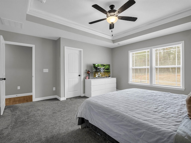 bedroom featuring a tray ceiling, ornamental molding, ceiling fan, and carpet