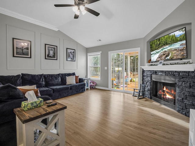 living room with ceiling fan, lofted ceiling, a stone fireplace, and light hardwood / wood-style floors