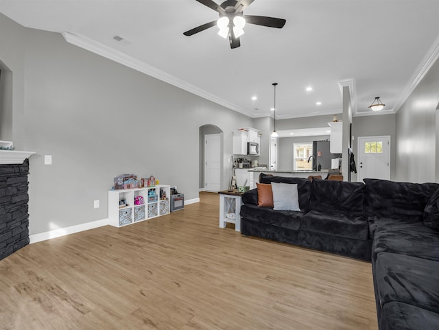 living room featuring ceiling fan, ornamental molding, sink, and light wood-type flooring