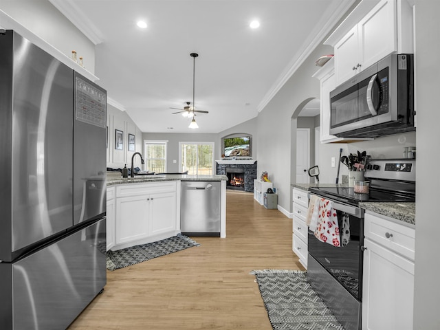 kitchen featuring appliances with stainless steel finishes, white cabinetry, sink, light stone countertops, and light hardwood / wood-style flooring