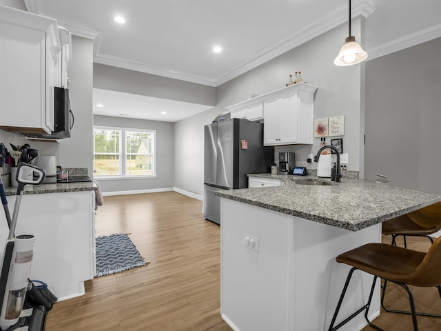 kitchen featuring white cabinetry, sink, stainless steel fridge, hanging light fixtures, and kitchen peninsula