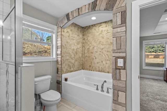 bathroom featuring tile patterned floors, a tub, and toilet