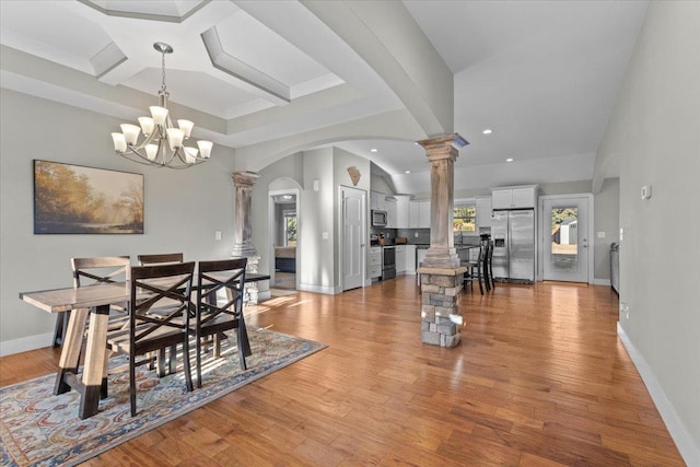 dining area featuring coffered ceiling, light hardwood / wood-style floors, an inviting chandelier, and ornate columns