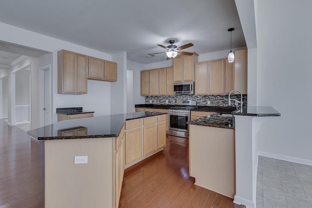 kitchen with stainless steel appliances, decorative light fixtures, sink, and dark stone countertops